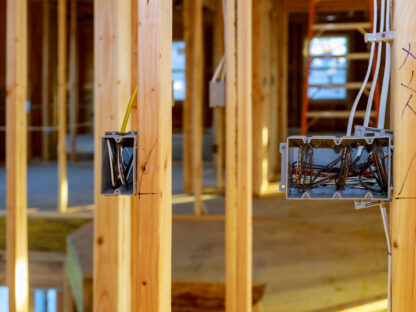 Wooden frame of a house under construction with exposed electrical wiring and outlet boxes.