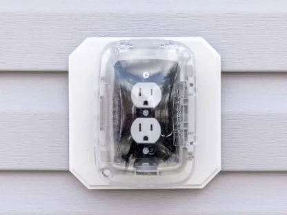 Outdoor electrical outlet with cover mounted on a vinyl siding wall.