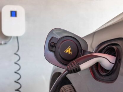 EV charger plugged into electric car.||
