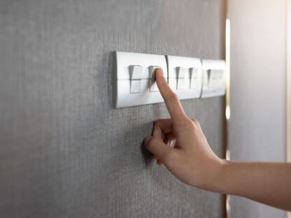 An image focusing on a hand turning off a light switch.||