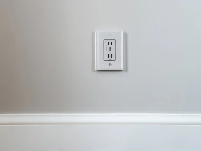 A white electrical outlet on a light gray wall above a wooden floor.||